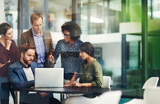 workers huddling over a computer in an office